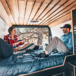 NC Biggie Campervan – 2 Berth-couple-sitting-in-bed